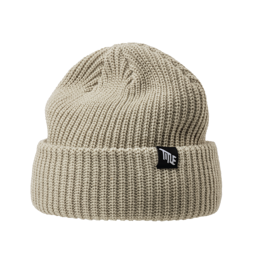 The Beanie by Title MTB is a beige acrylic knit with folded brim and black tag, perfect for keeping warm.