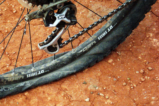 Close-up of a flat mountain bike tire, showing the deflated tube and rim.