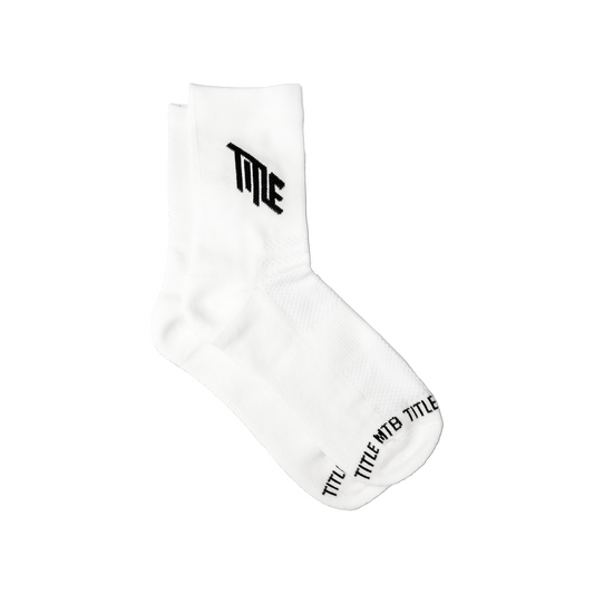 Title MTB's The Everyday Socks: comfy white crew socks with black TILE text on the cuff and TITLE WTB TITLE on the toe.